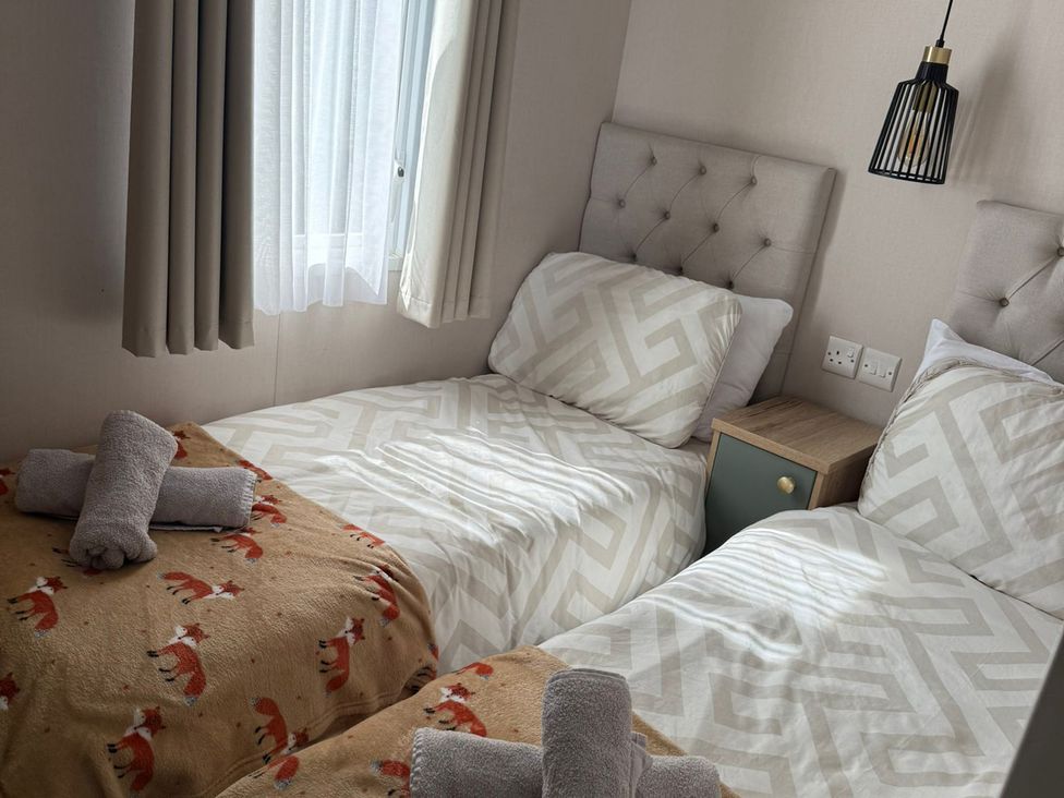 A bedroom with twin beds and a bedside table at Seren in Broughton, Cumbria