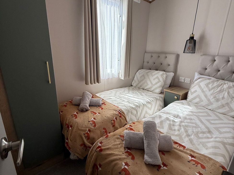 A bedroom with two beds and a wardrobe at Seren Broughton, Cumbria