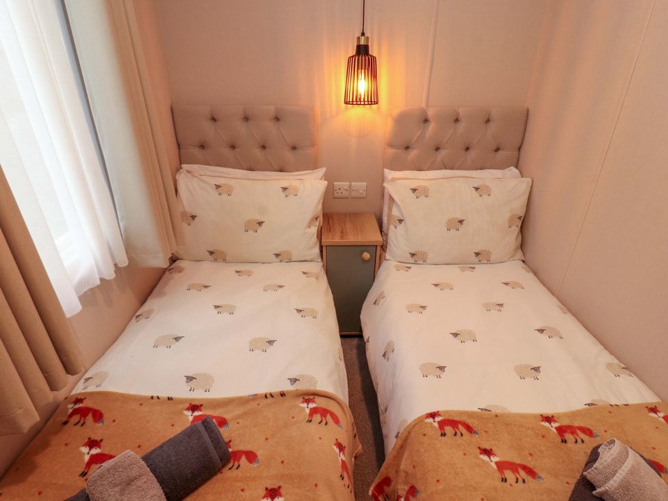 A bedroom with two single beds and a bedside table at Seren, Broughton, Cumbria