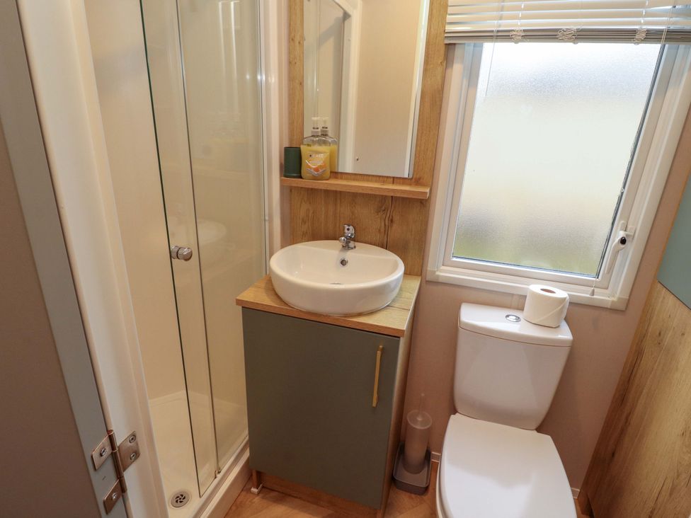 A bathroom with a shower, sink, and toilet at Seren in Broughton, Cumbria