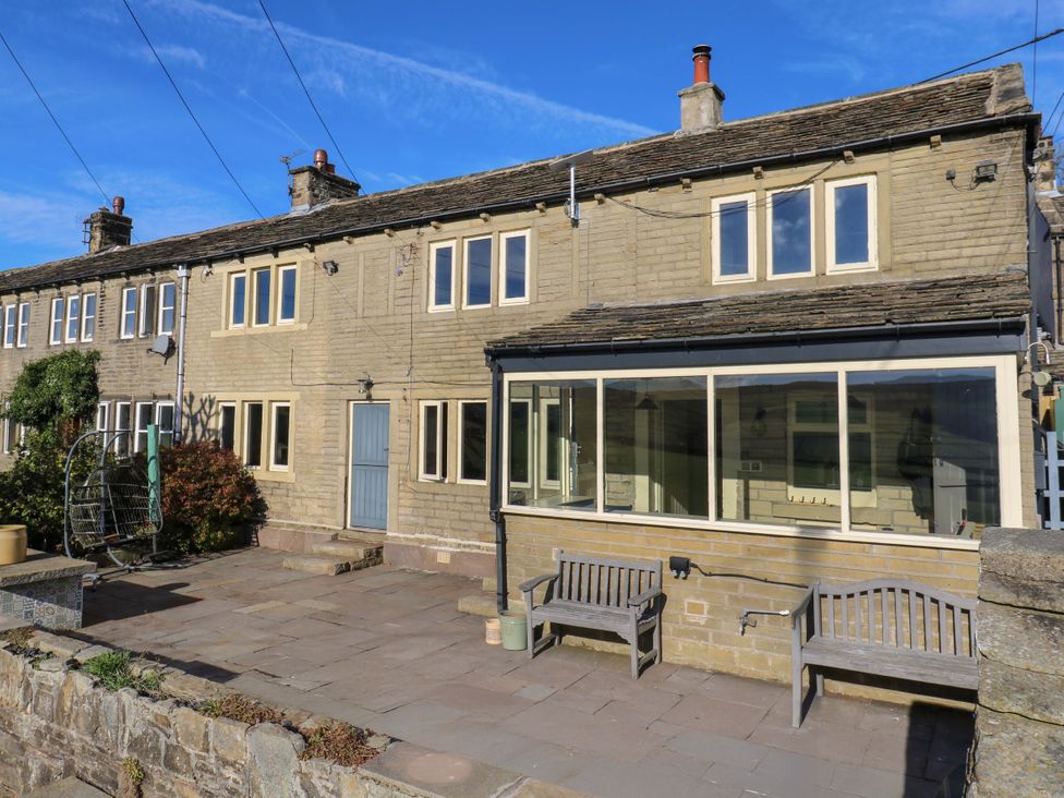 An outdoor view of a house with benches and windows at 1 Flush House Lane, Holmbridge