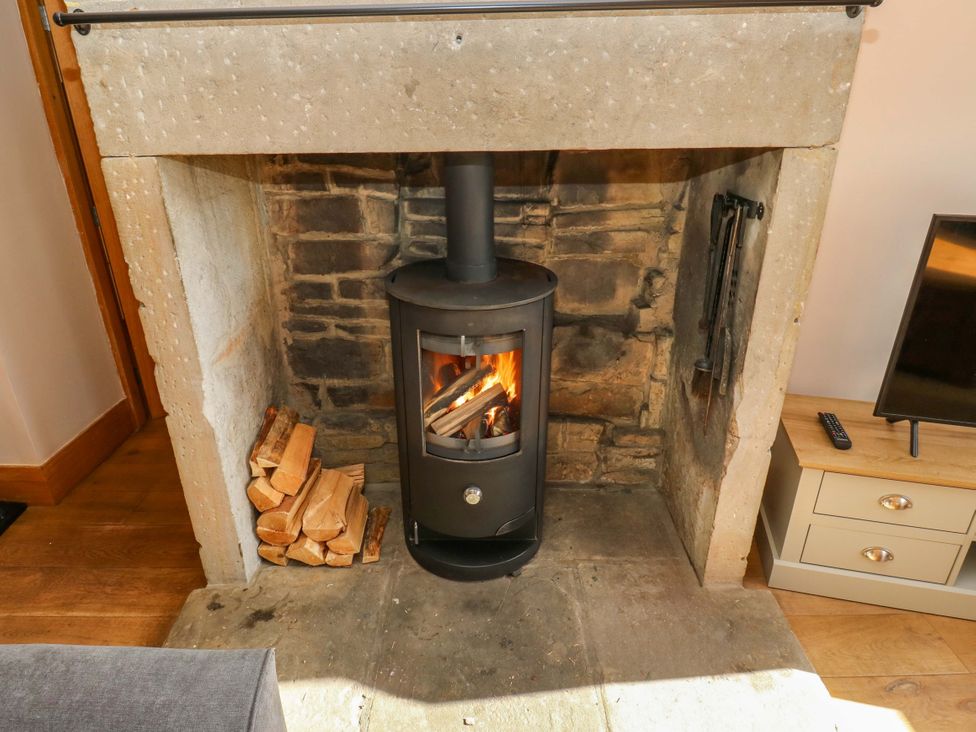 A fireplace with a wood stove and firewood at 1 Flush House Lane Holmbridge