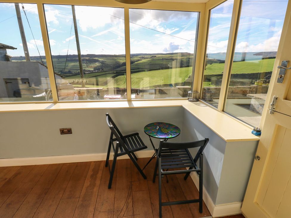 A conservatory with a table and chairs at 1 Flush House Lane Holmbridge