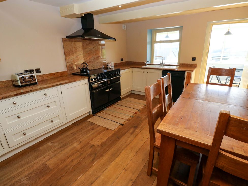 A kitchen with a stove and dining table at 1 Flush House Lane in Holmbridge