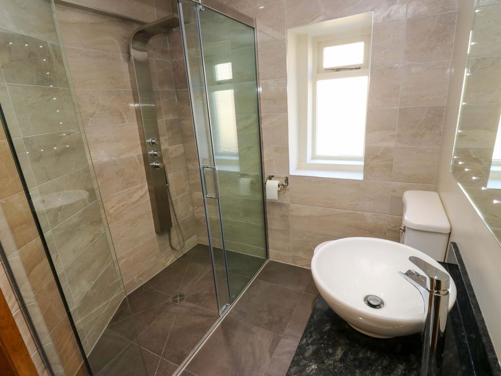 A bathroom with a shower, toilet, and sink at 1 Flush House Lane in Holmbridge