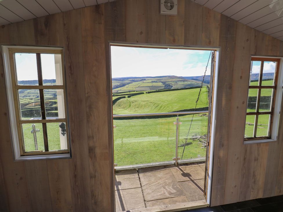 A room with a door and window leading to a balcony at 1 Flush House Lane in Holmbridge