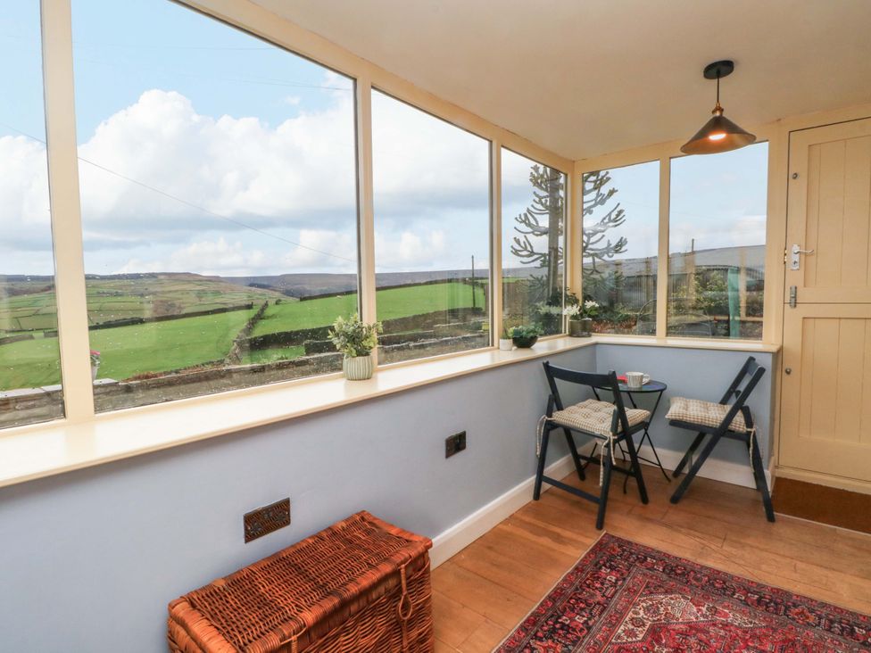 A conservatory with a table and chairs at Stone & Fleece Cottage in Holmbridge