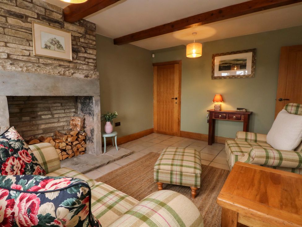 A living room with a fireplace and armchairs at Stone & Fleece Cottage in Holmbridge