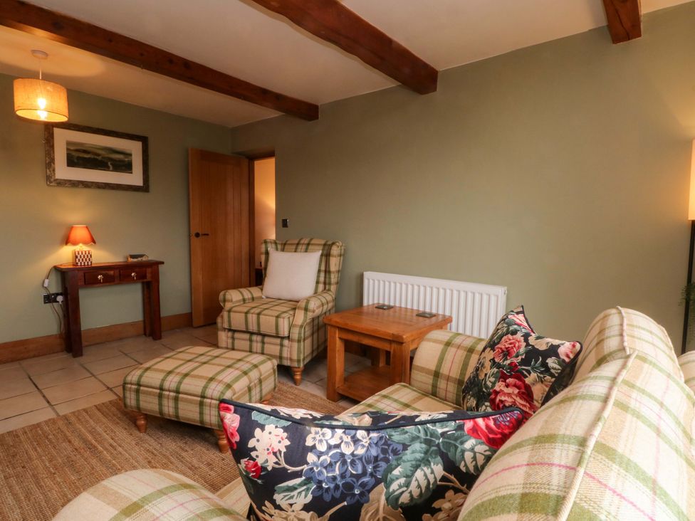 A living room with a sofa and armchair at Stone & Fleece Cottage in Holmbridge