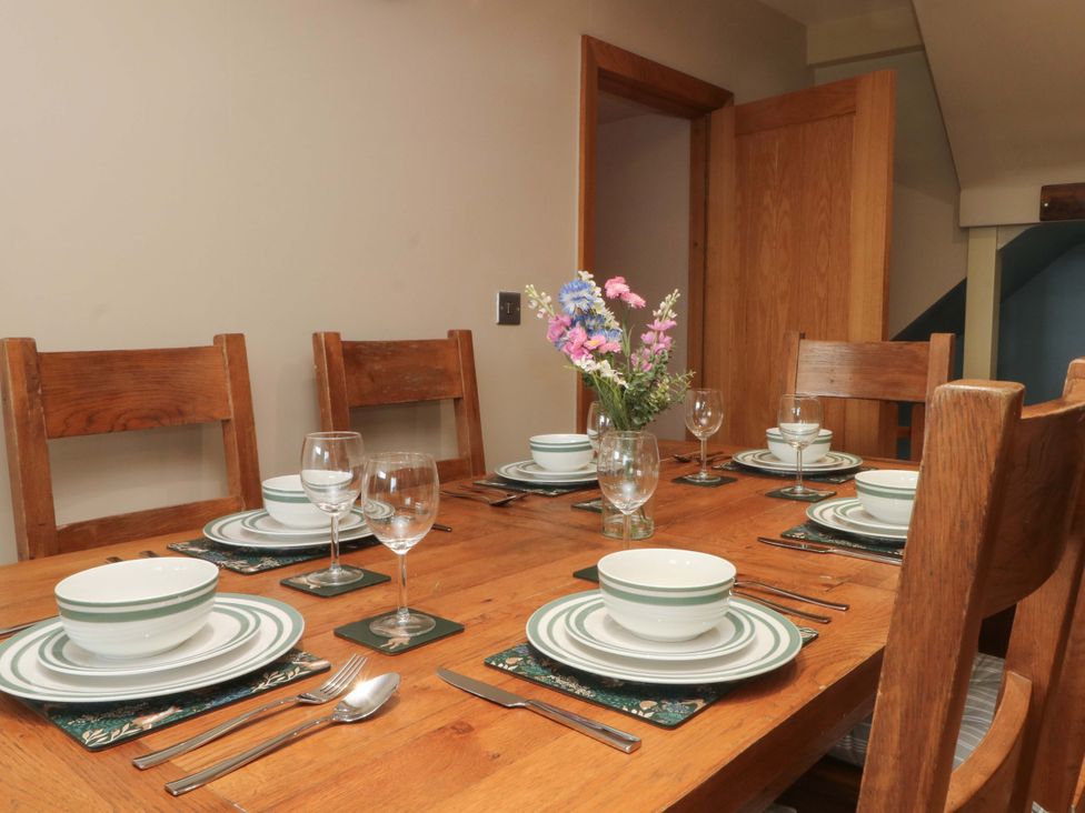 A dining room with a table set for a meal at Stone & Fleece Cottage, Holmbridge