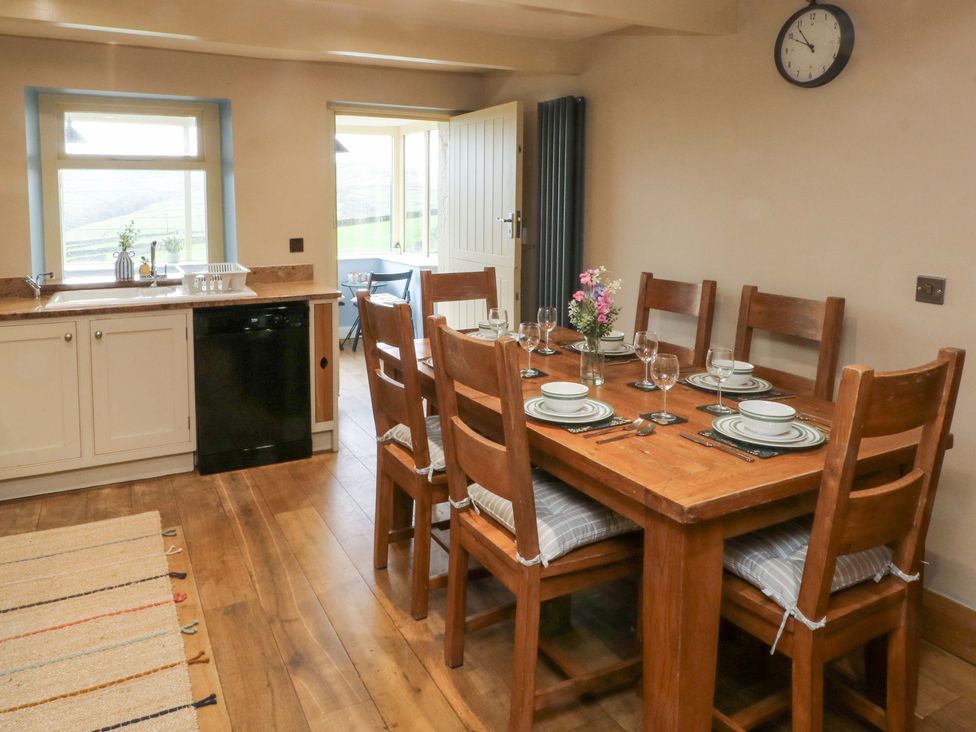 A kitchen with a dining table and chairs at Stone & Fleece Cottage in Holmbridge