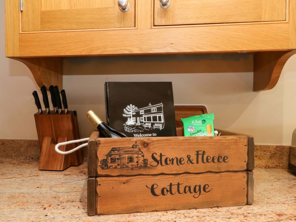A kitchen with a basket containing a guest book and snacks at Stone & Fleece Cottage in Holmbridge