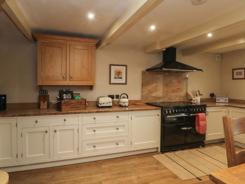 A kitchen with cabinets, stove, microwave, and countertop at Stone & Fleece Cottage in Holmbridge