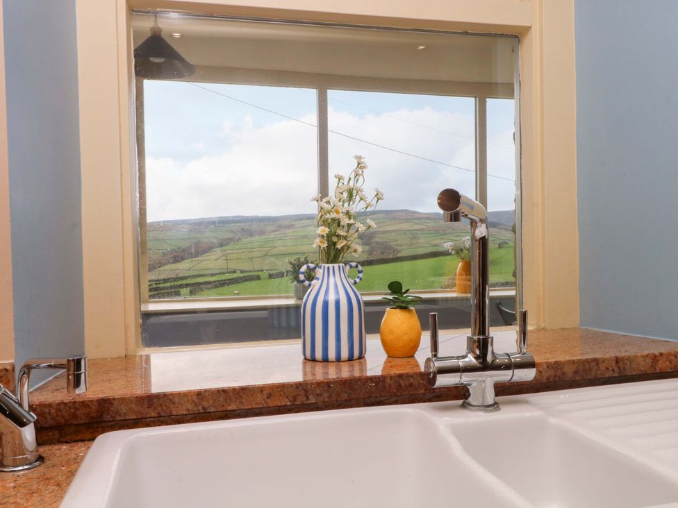 A kitchen with a sink and faucet overlooking hills at Stone & Fleece Cottage Holmbridge