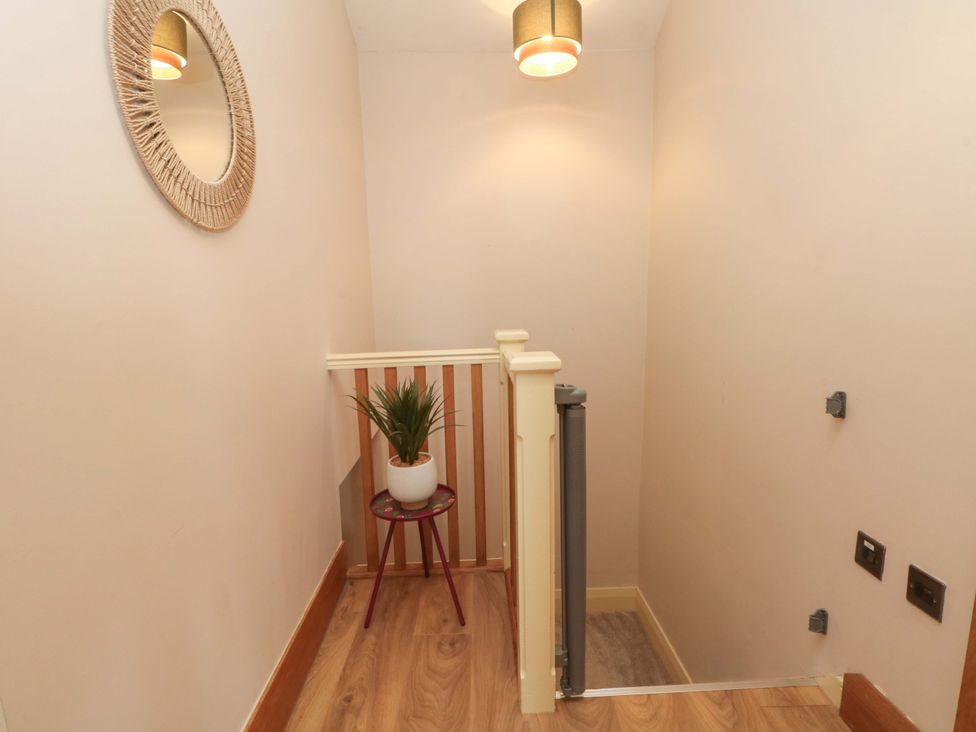 A hallway with a plant on a table and a mirror at Stone & Fleece Cottage Holmbridge