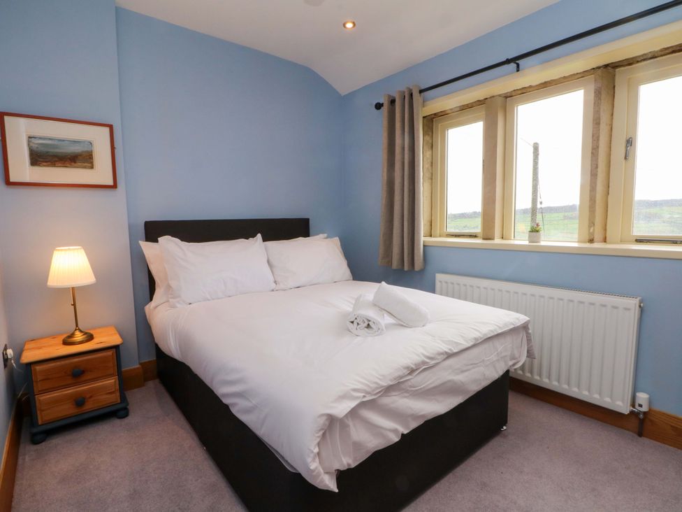 A bedroom with a bed and window at Stone & Fleece Cottage in Holmbridge