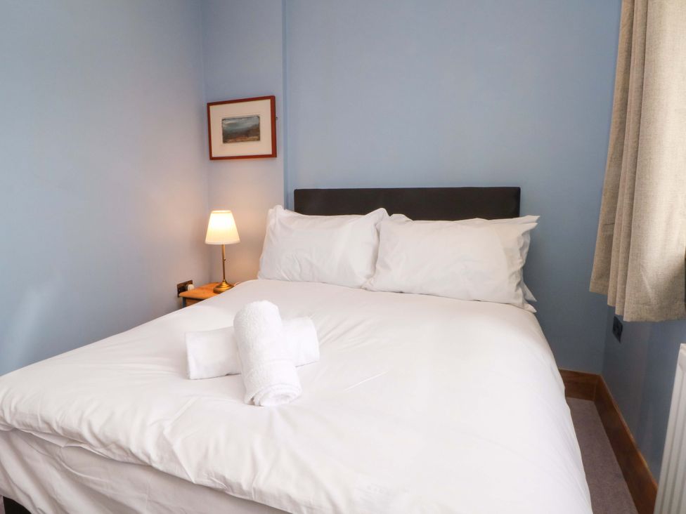 A bedroom with a bed and bedside lamp at Stone & Fleece Cottage, Holmbridge