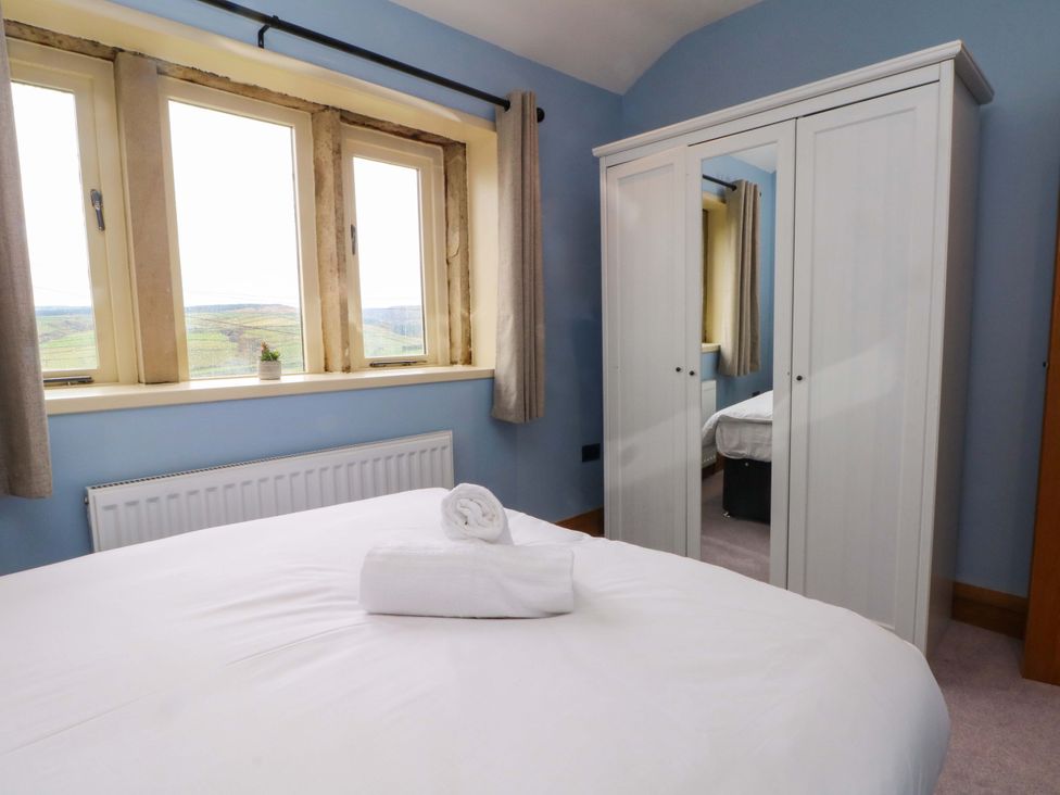 A bedroom with a bed and wardrobe at Stone & Fleece Cottage in Holmbridge