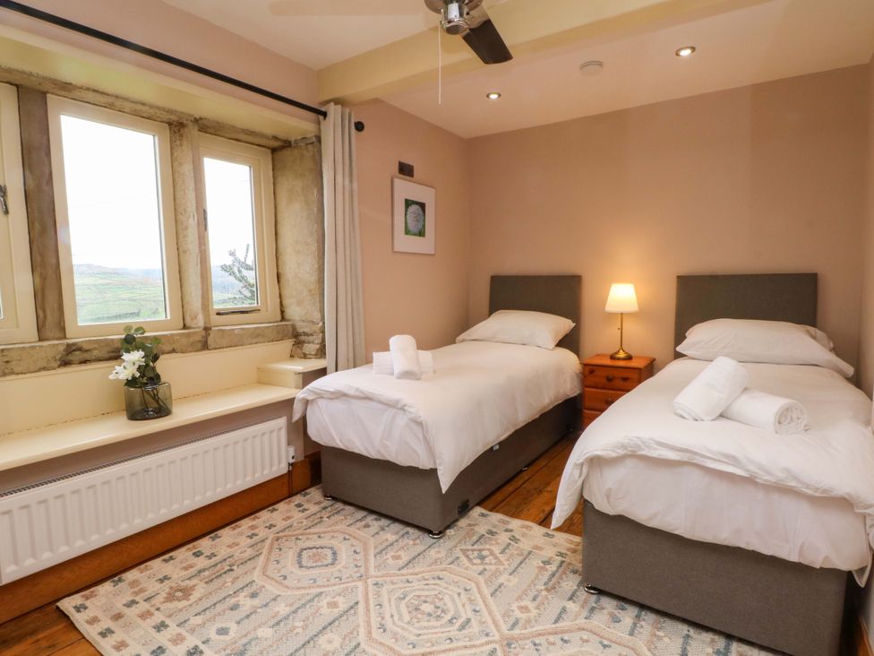 A bedroom with two beds and a window at Stone & Fleece Cottage Holmbridge