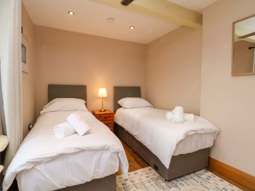 A bedroom with two single beds and a bedside table at Stone & Fleece Cottage in Holmbridge