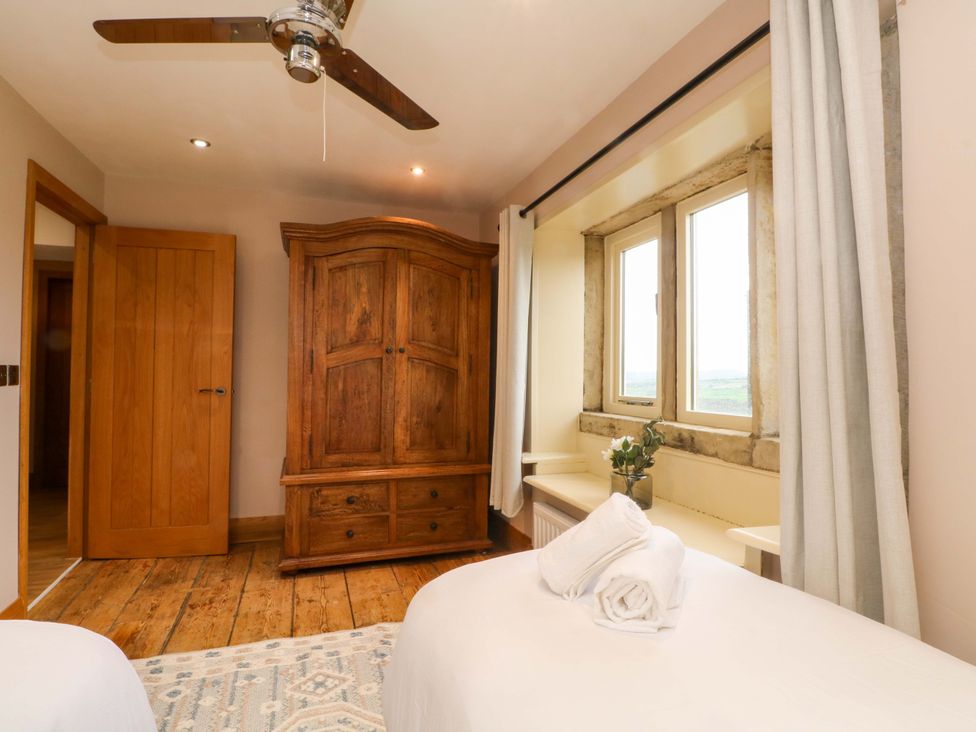 A bedroom with a wardrobe and window at Stone & Fleece Cottage in Holmbridge