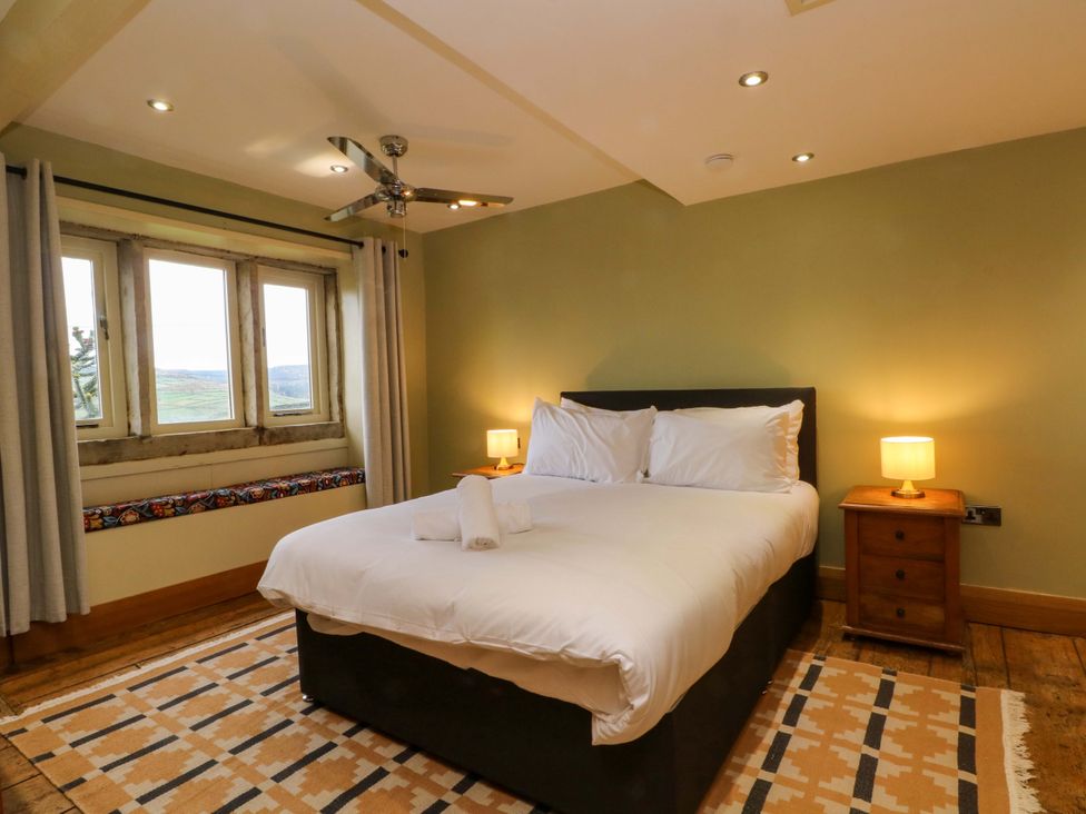 A bedroom with a bed and a nightstand at Stone & Fleece Cottage in Holmbridge