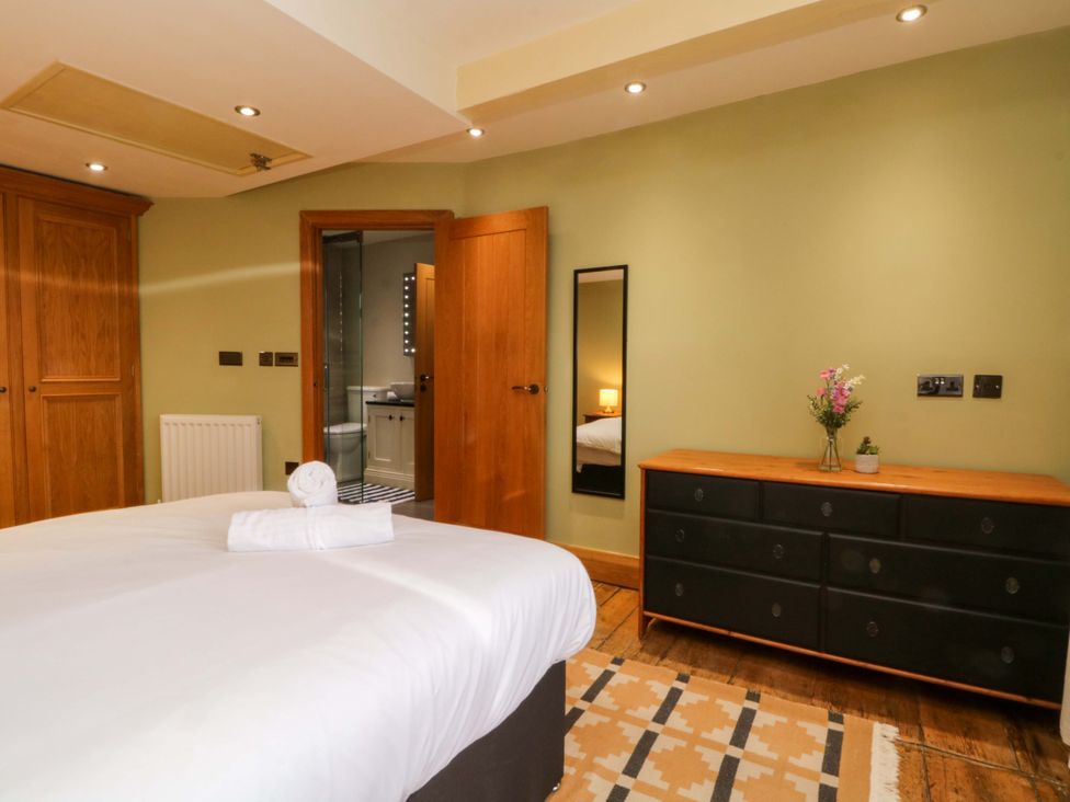 A bedroom with a bed and dresser at Stone & Fleece Cottage in Holmbridge