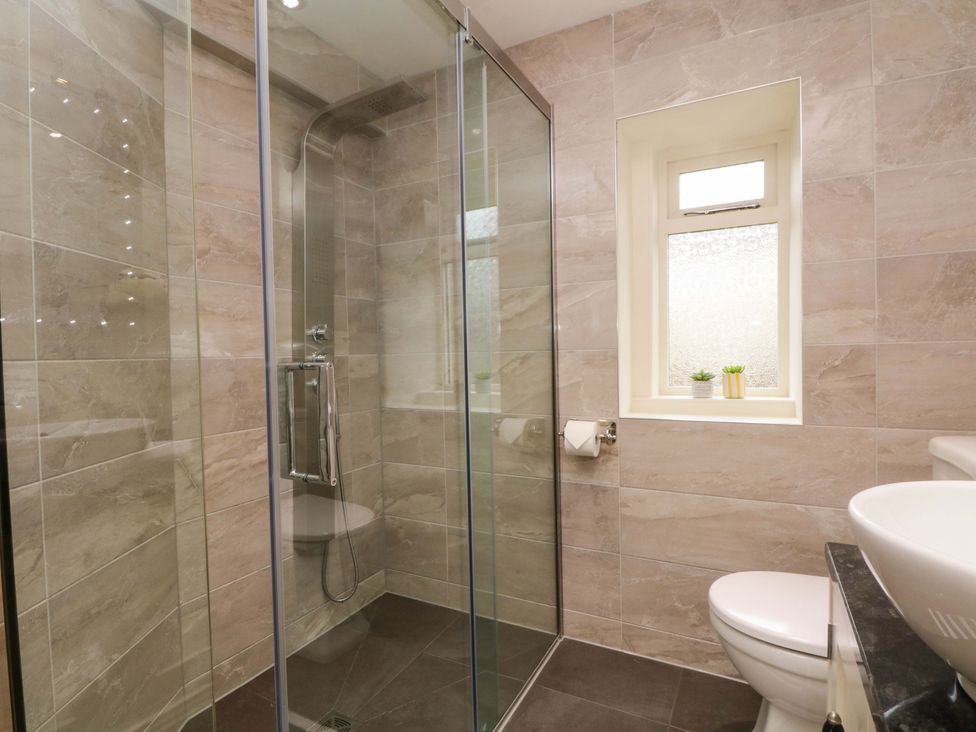 A bathroom with a shower, toilet, and sink at Stone & Fleece Cottage in Holmbridge