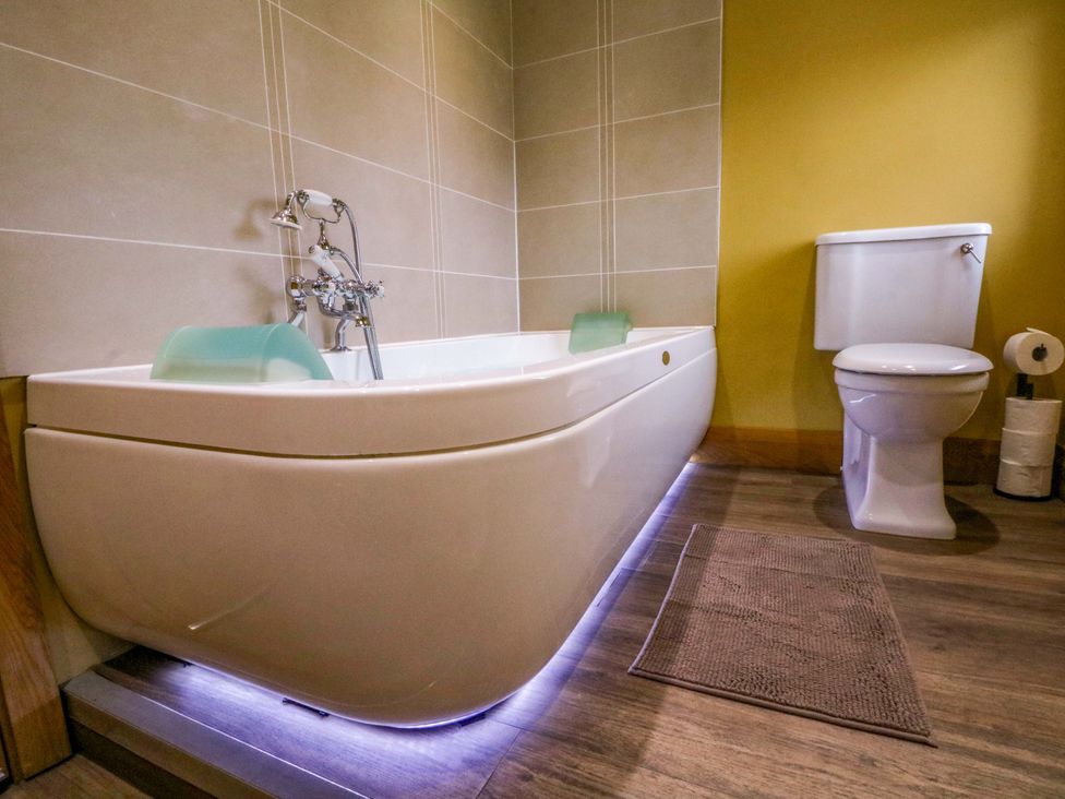 A bathroom with a bathtub and toilet at Stone & Fleece Cottage Holmbridge