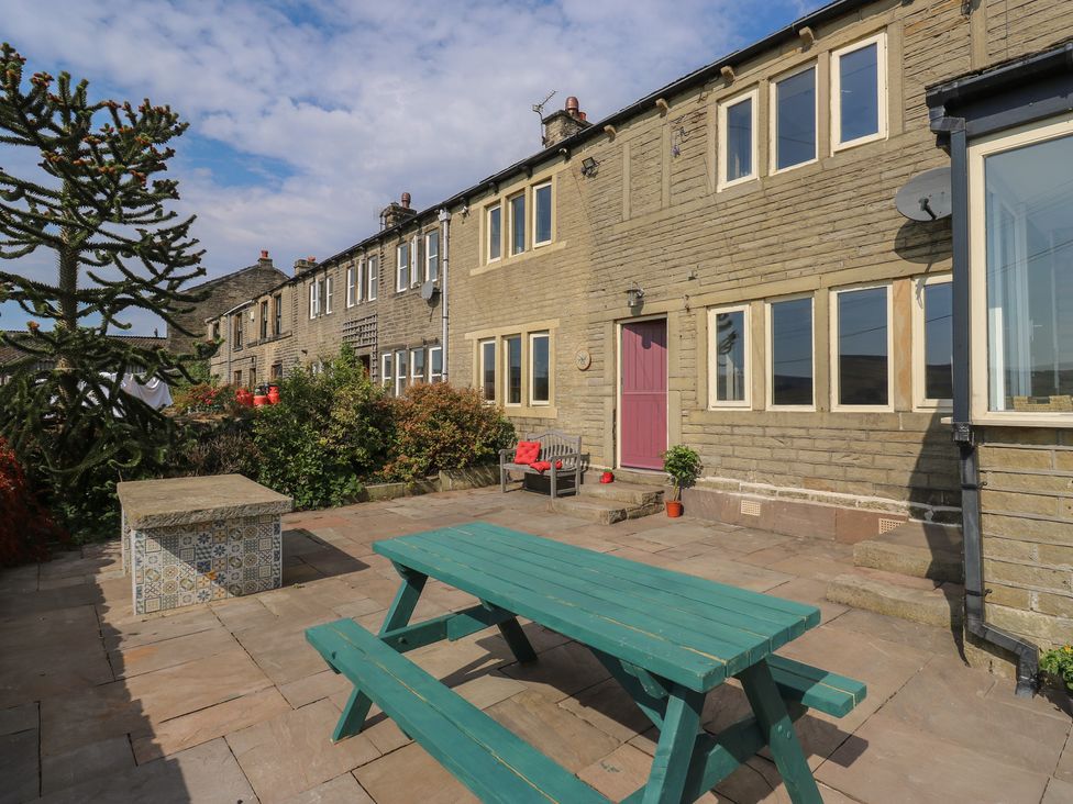 An outdoor area with a table and bench at Stone & Fleece Cottage in Holmfirth