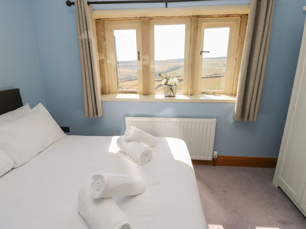 A bedroom with a bed and towels at Stone & Fleece Cottage in Holmfirth