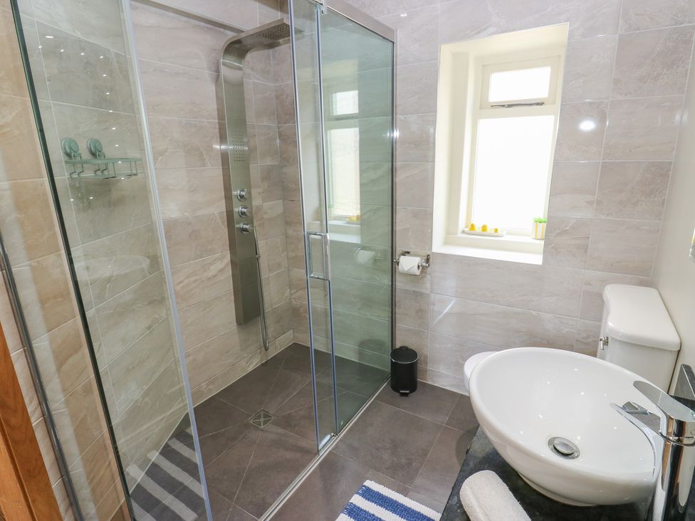 A bathroom with a shower, wash basin, and toilet at Stone & Fleece Cottage in Holmfirth