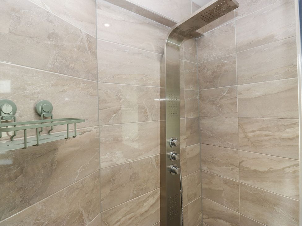 A shower with a wall-mounted faucet and shelf at Stone & Fleece Cottage in Holmfirth