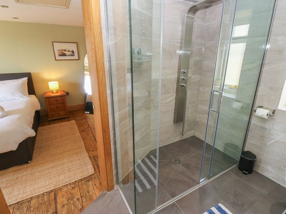 A bathroom with a shower and an adjacent bedroom at Stone & Fleece Cottage in Holmfirth