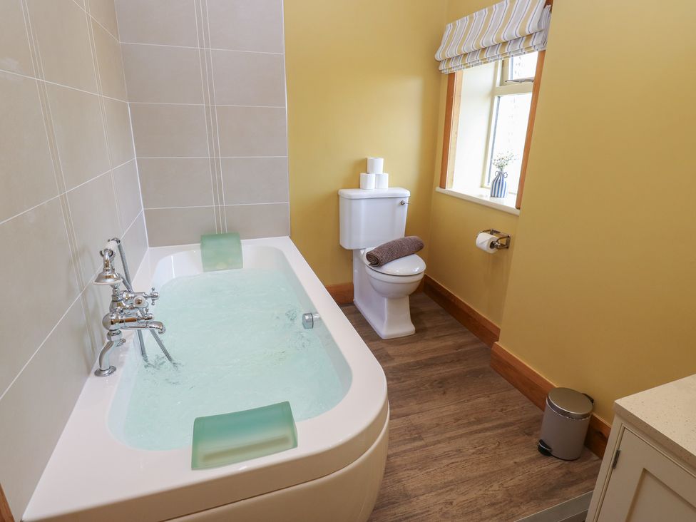 A bathroom with a bathtub and toilet at Stone & Fleece Cottage Holmfirth