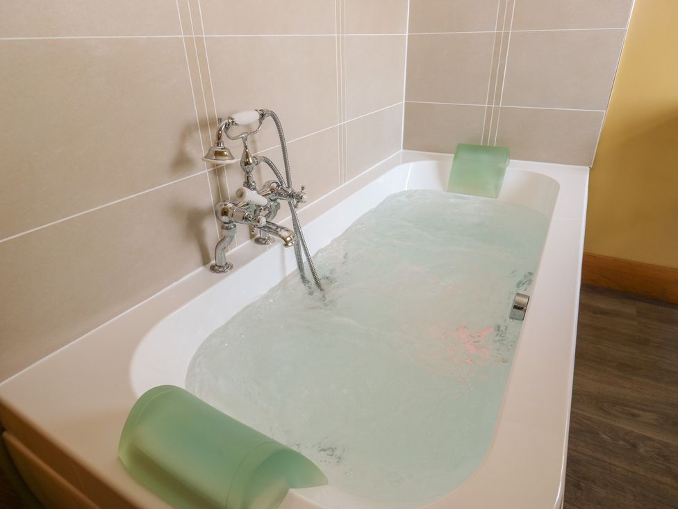 A bathtub with water and a faucet at Stone & Fleece Cottage Holmfirth