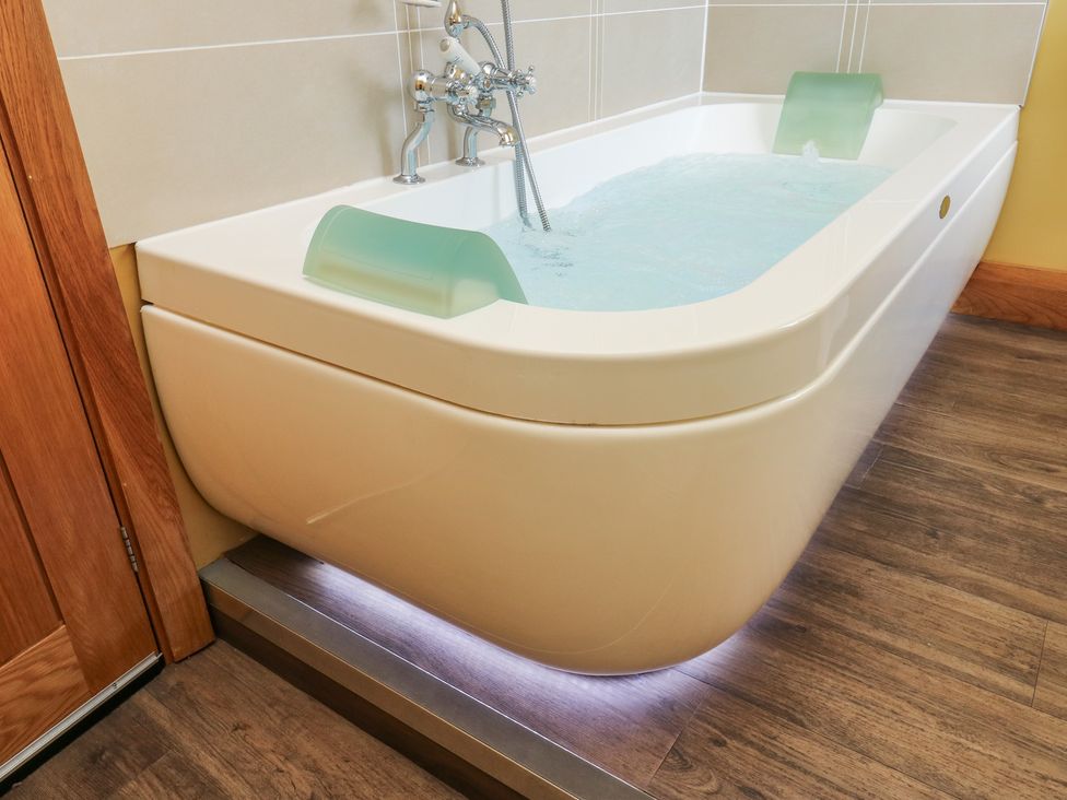 A bathtub with water and faucet at Stone & Fleece Cottage in Holmfirth