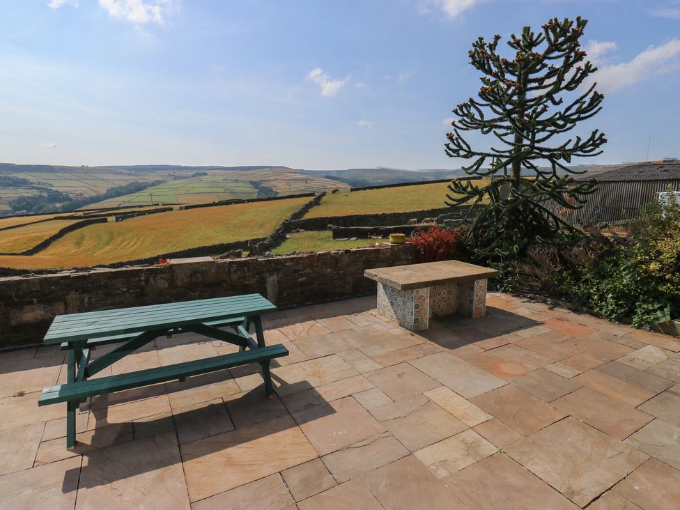 An outdoor patio with a picnic table and stone table at Stone & Fleece Cottage in Holmfirth