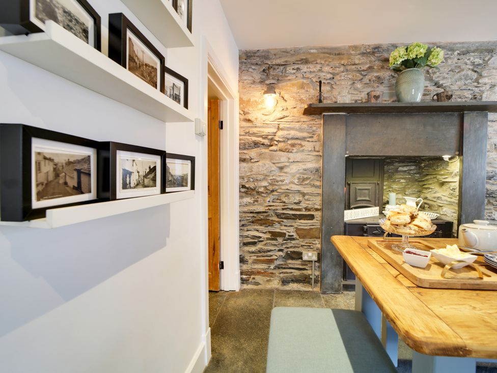 A kitchen with a table and photographs on a shelf at Church Hill House in Port Isaac