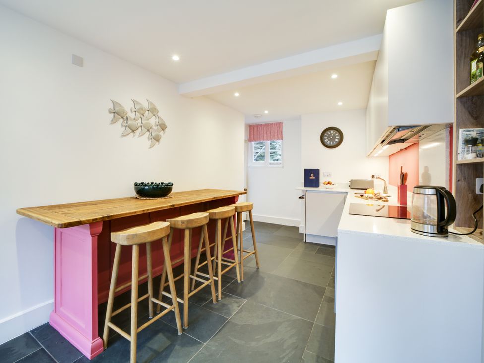 A kitchen with a counter and bar stools at Church Hill House in Port Isaac