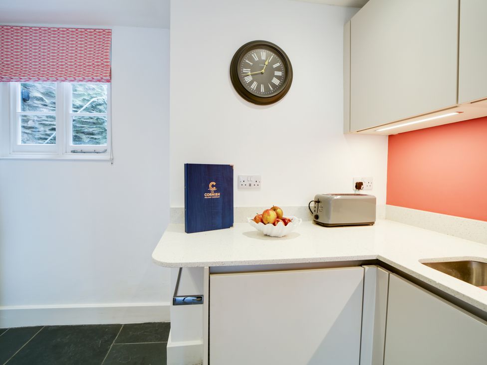 A kitchen with a clock and a fruit bowl at Church Hill House in Port Isaac