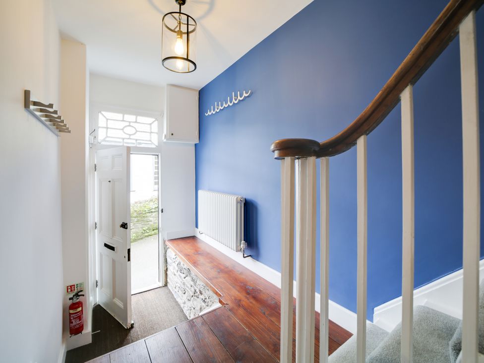 A hallway with a bench and a staircase at Church Hill House in Port Isaac