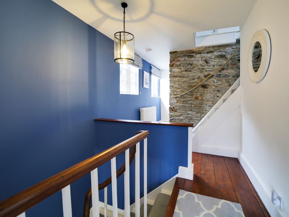 A staircase with a blue wall and light fixture at Church Hill House in Port Isaac