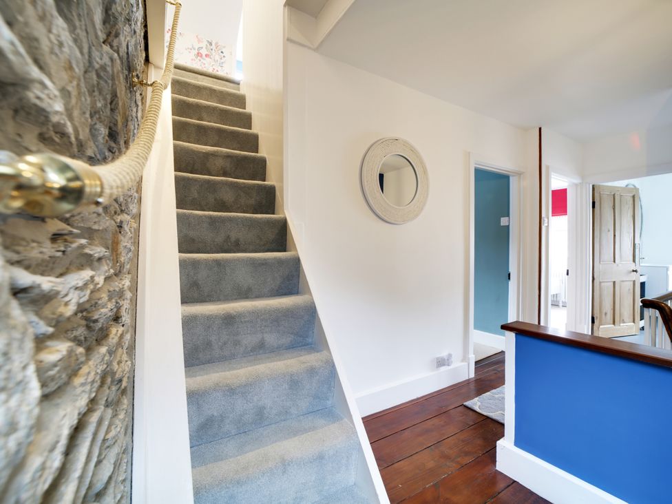 A staircase with a handrail in the hallway at Church Hill House in Port Isaac