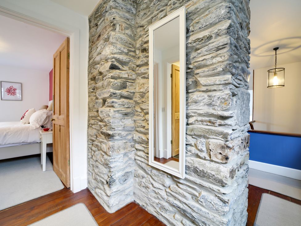 A hallway with a stone wall and mirror at Church Hill House in Port Isaac