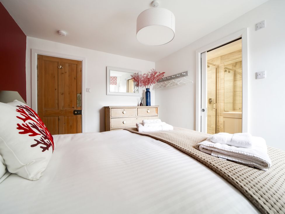 A bedroom with a dresser and an attached bathroom at Church Hill House in Port Isaac