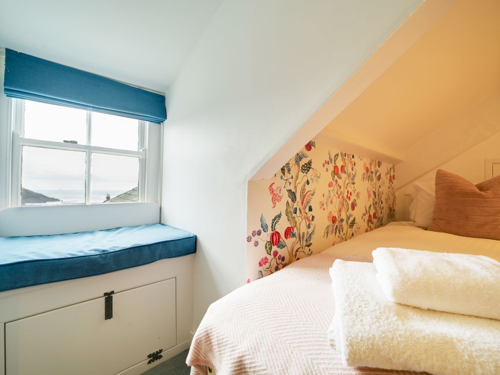 A bedroom with a bed and window seat at Church Hill House in Port Isaac