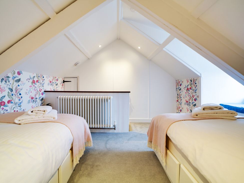 A bedroom with two beds and floral wallpaper at Church Hill House in Port Isaac