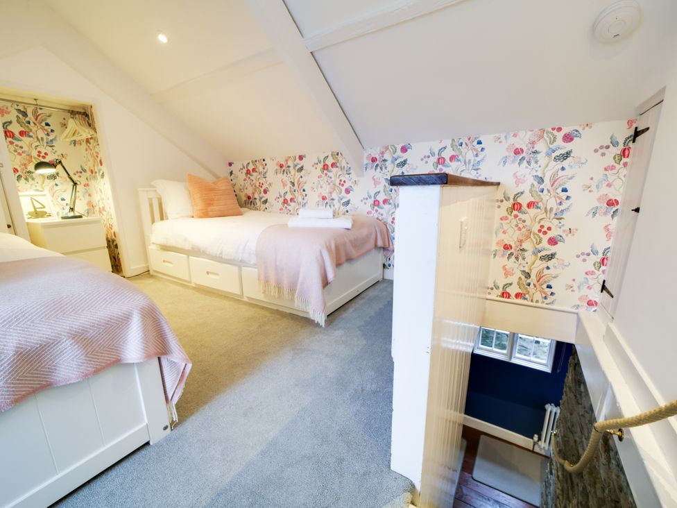 A bedroom with two beds and a staircase at Church Hill House in Port Isaac