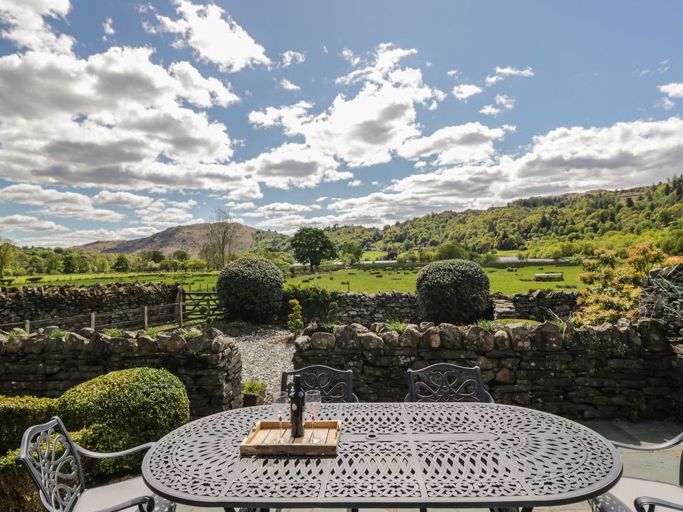 An outdoor space with a table and chairs overlooking hills at The Barn at Grasmere in Grasmere